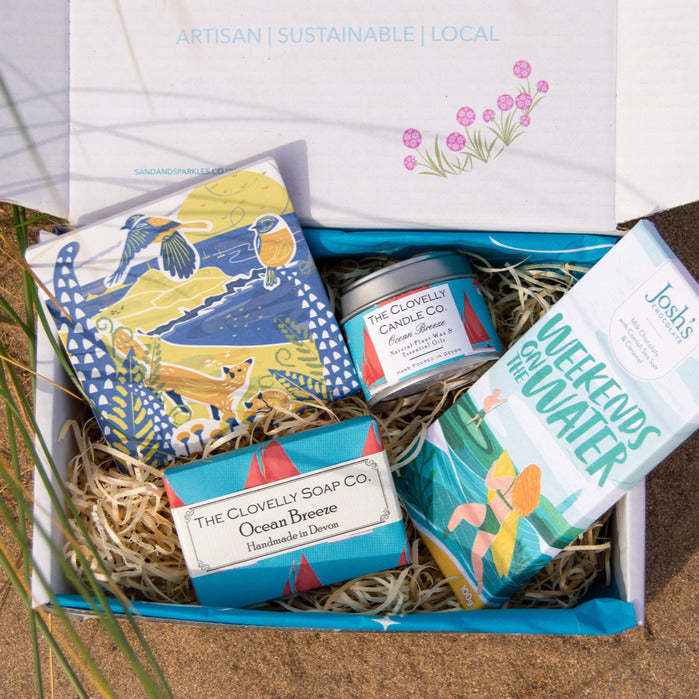 Beach Lovers Gift Box with Cornish Coaster, Devon handmade soap and ocean breeze candle, Cornish chocolate in a Sand and Sparkle gift box pictured at the beach