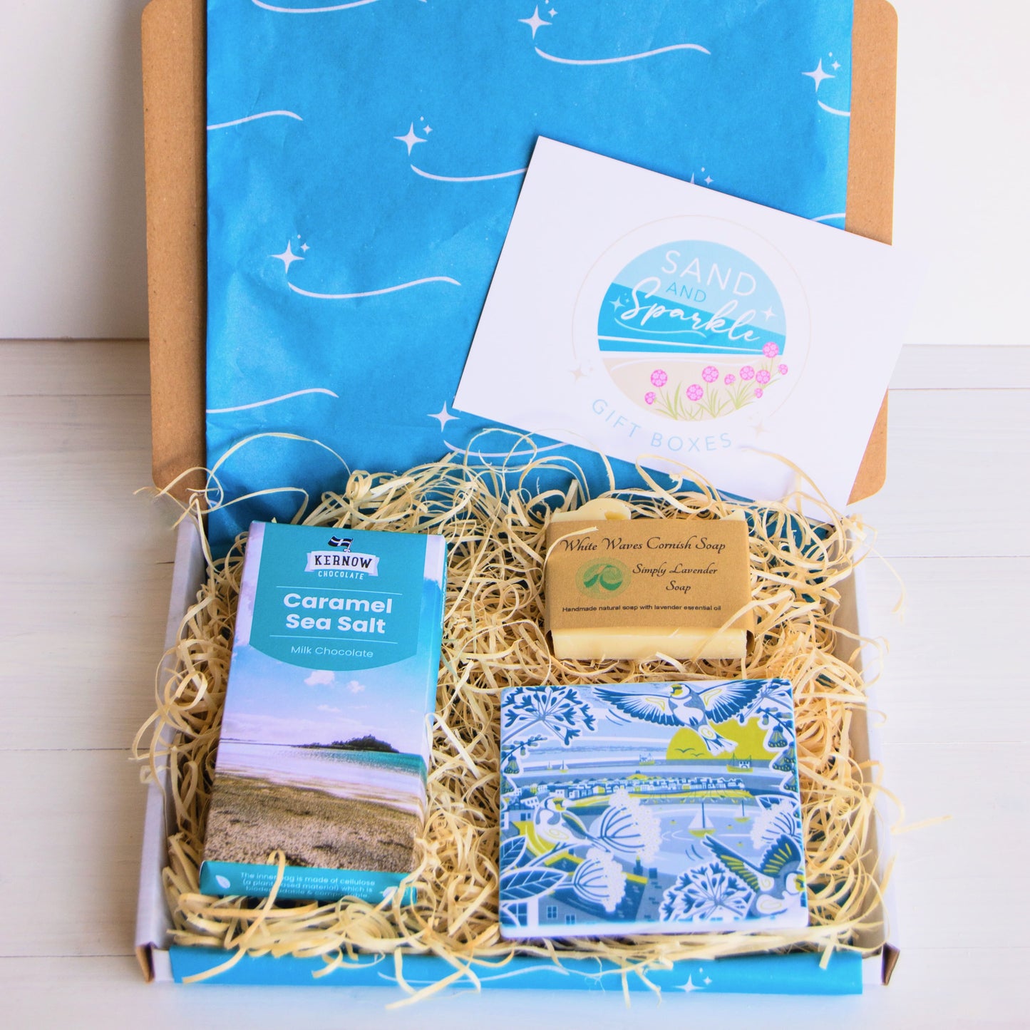 cornish coastal letterbox gift set with illustrated coaster, artisan chocolate and handcrafted soap