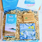 Cornish Coastal Letterbox Gift Set with illustrated Cornish coaster from Jennifer Armitage, Kernow Chocolate and White Waves Cornish Soap. IN coastal themed letterbox with gift card.