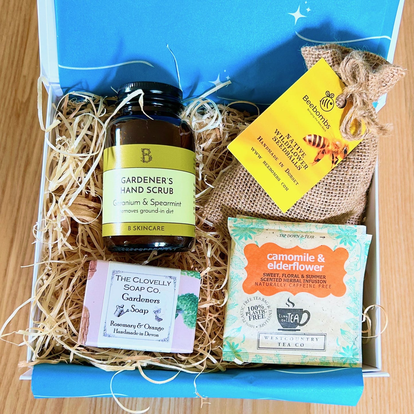 Gardener's gift  hamper with 'Gardener's Hand Scrub', 'Gardeners Soap', and 'Camomile & Elderflower' tea in a box as well as Beebombs wild flower seeds to create a wild flower meadow.