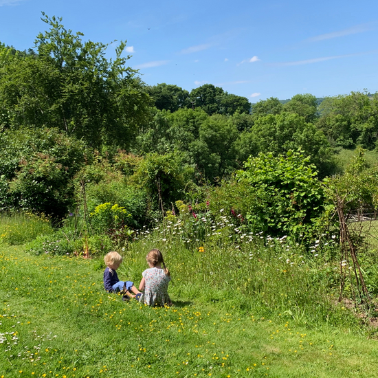 Two children sit in a garden in Devon